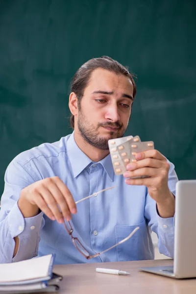 Young sick male teacher in the classroom — Stock Photo, Image