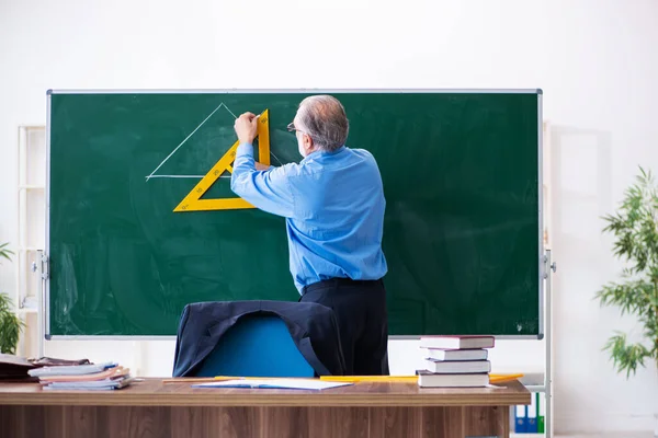 Viejo profesor de geometría masculina sosteniendo triángulo — Foto de Stock