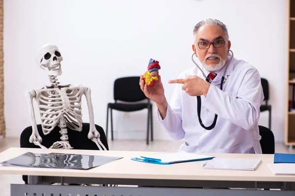 Anciano médico cardiólogo y paciente esqueleto en la clínica —  Fotos de Stock