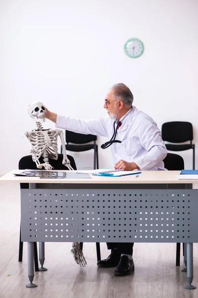 Klinikteki yaşlı erkek doktor ve iskelet hastası. — Stok fotoğraf