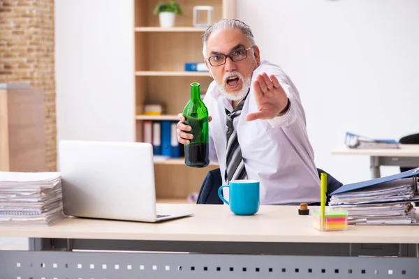 Un vieil employé boit de l'alcool au bureau — Photo