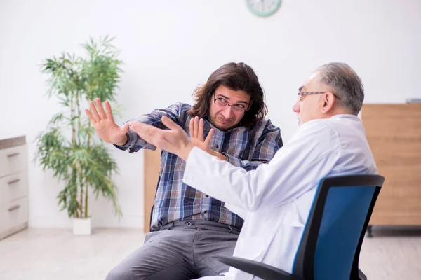 Jonge mannelijke patiënt op bezoek bij ervaren arts-psychiater — Stockfoto