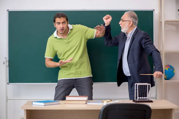 Aged teacher and male lazy student in the classroom