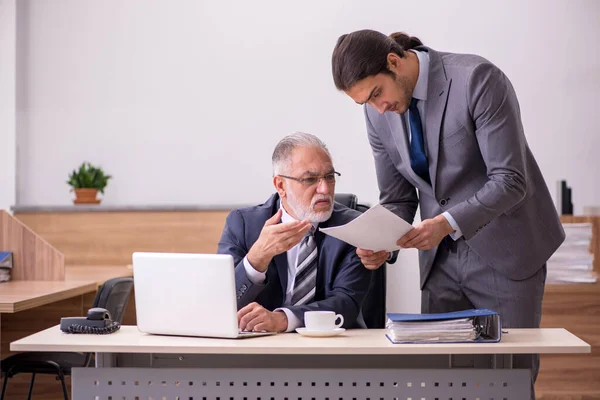 Oude baas en jonge mannelijke assistent in het kantoor — Stockfoto