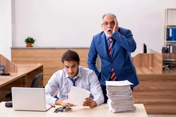 Young male employee and old boss burning papers at workplace — Stock Photo, Image