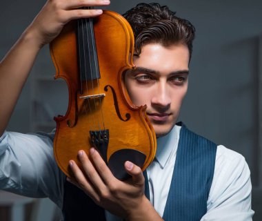 Genç müzisyen evde keman çalıyor.