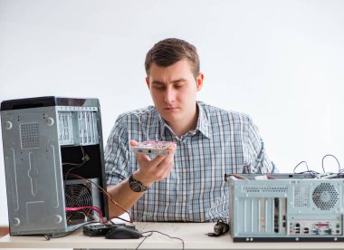 Genç teknisyen atölyede bilgisayar tamir ediyor.