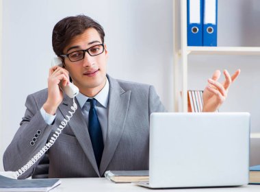 İşadamı ofis telefonundan konuşuyor.