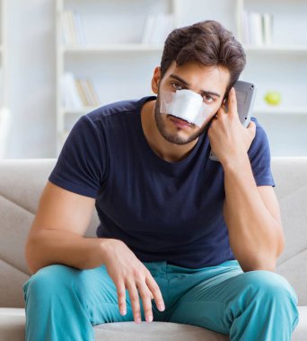 Genç adam estetik cerrahi burnundan sonra evde iyileşiyor.