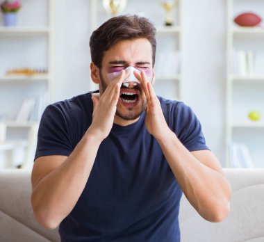 Genç adam estetik cerrahi burnundan sonra evde iyileşiyor.