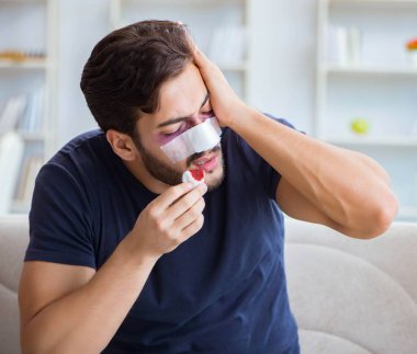 Genç adam estetik cerrahi burnundan sonra evde iyileşiyor.