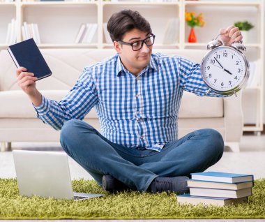 Genç yakışıklı adam evde yerde oturuyor.