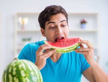 Evde karpuz yiyen bir adam.