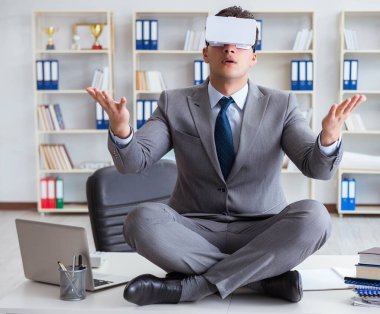 Sanal gerçeklikteki iş adamı VR gözlükleri masanın üstünde meditasyon yapıyor.