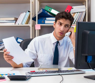 Ofiste kitap ve kağıtlarla çalışan bir işadamı.