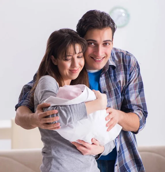 Young parents with their newborn baby near bed cot — Stock Photo, Image