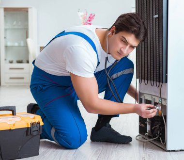 Tamirci müteahhit DIY konseptinde buzdolabını tamir ediyor.
