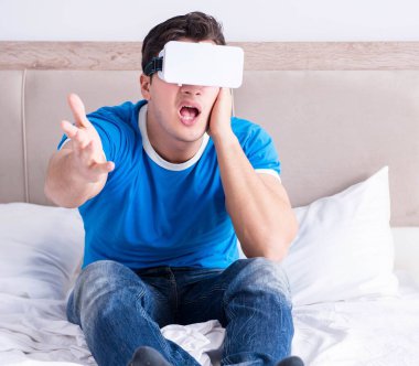Yatakta sanal gerçeklik başlığı takan genç bir adam.