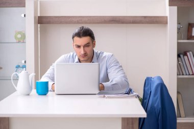 Evde çalışan genç bir erkek.