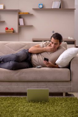 Evdeki kanepede yatan genç adam.