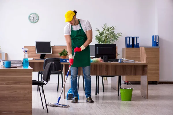 Jovem empreiteiro limpando o escritório — Fotografia de Stock