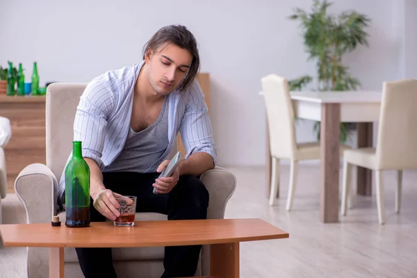 Jovem alcoólico masculino assistindo tv após festa — Fotografia de Stock
