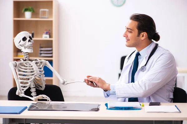 Jonge mannelijke arts en skelet patiënt in de kliniek — Stockfoto