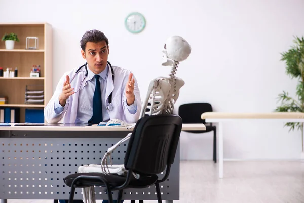 Jonge mannelijke arts en skelet patiënt in de kliniek — Stockfoto