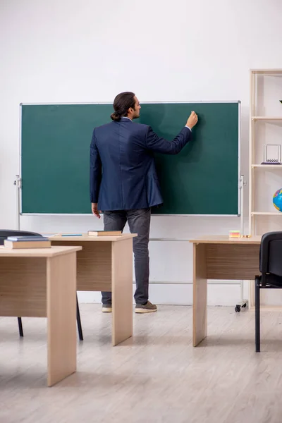 Jonge mannelijke leraar in de voorkant van groene boord — Stockfoto