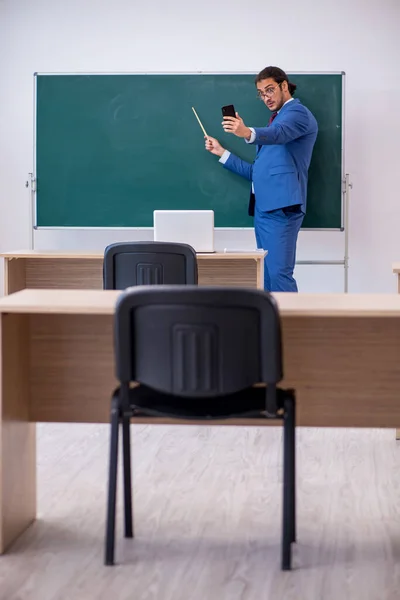 Mladý muž učitel v obleku před zelenou tabuli — Stock fotografie