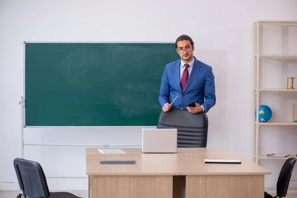 緑のボードの前でスーツの若い男性教師 — ストック写真