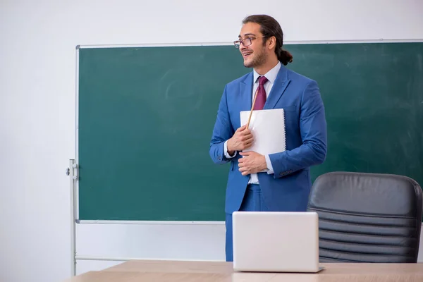 Joven profesor de traje delante del tablero verde —  Fotos de Stock