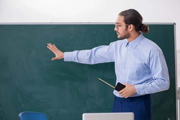 Giovane insegnante di sesso maschile in classe di fronte a bordo verde — Foto Stock
