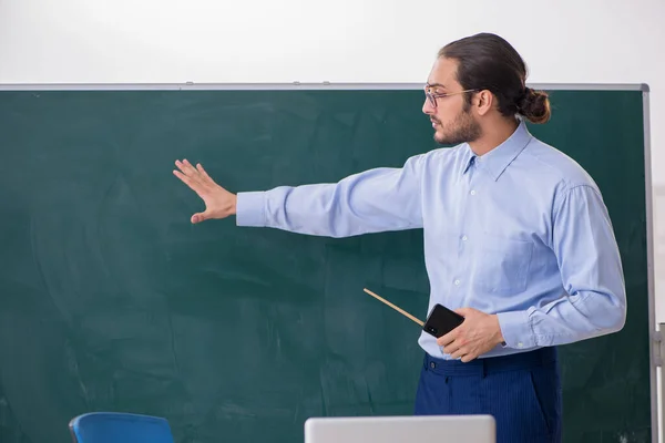 Joven profesor en el aula delante de la mesa verde —  Fotos de Stock