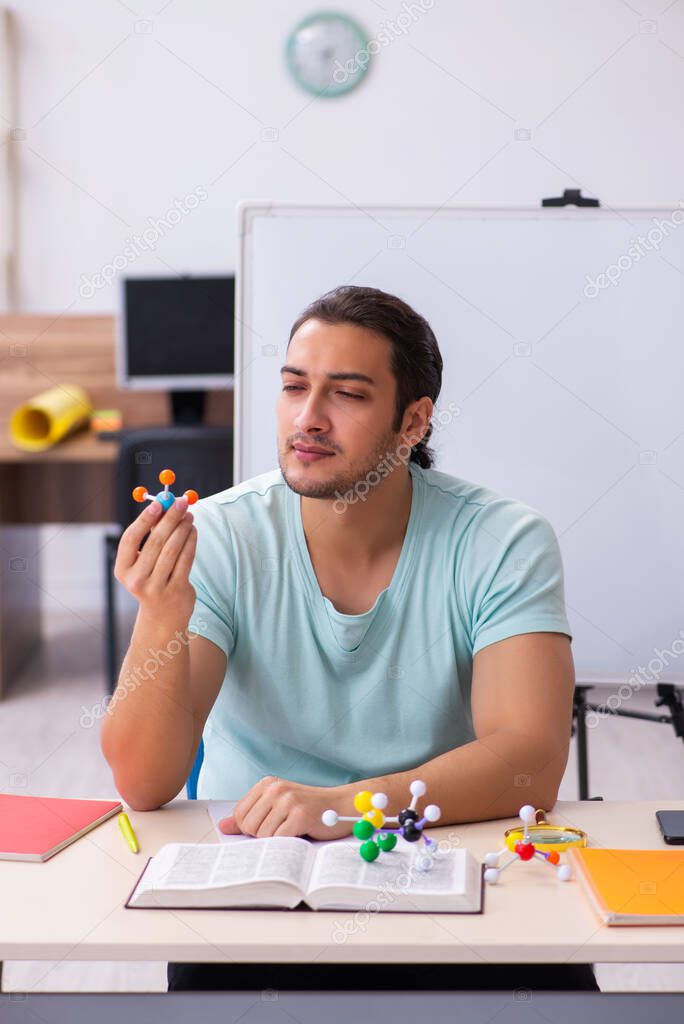 Young male student physicist studying molecular model at home