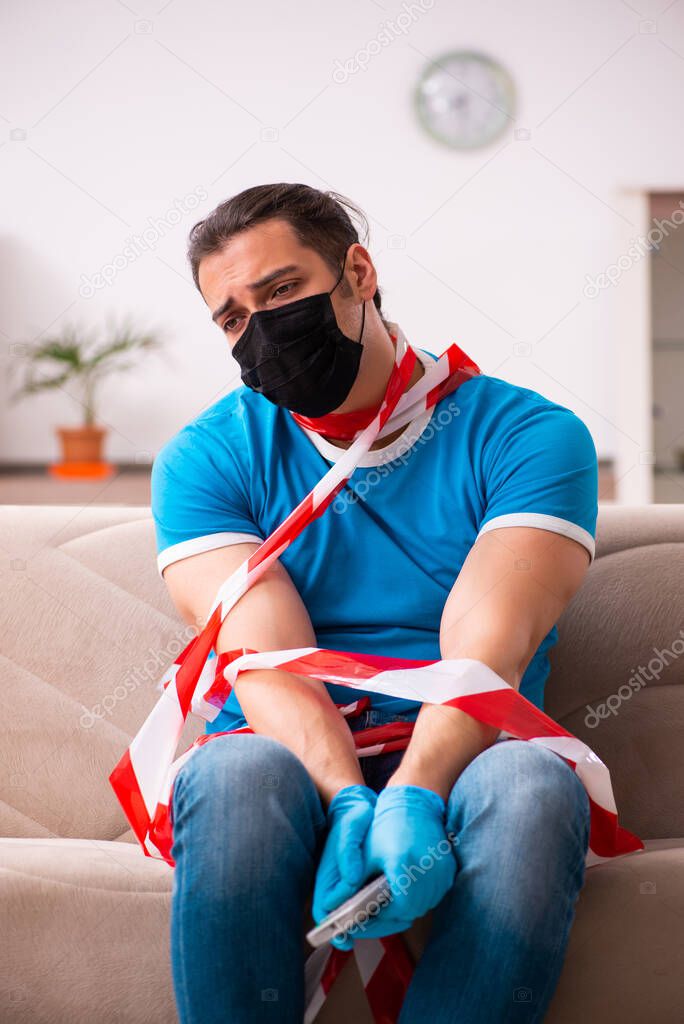 Young man watching tv at home in pandemic concept