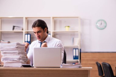 Ofisteki aşırı işten memnun olmayan genç bir erkek işçi.