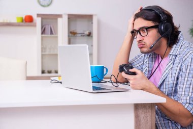 Evde bilgisayar oyunu oynayan genç bir erkek öğrenci