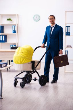 Genç erkek çalışan işyerinde çocuğa bakıyor.