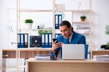 Genç yakışıklı çalışan ofiste oturuyor.