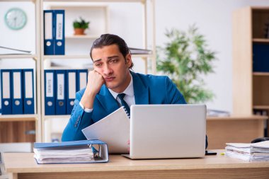 Genç yakışıklı çalışan ofiste oturuyor.