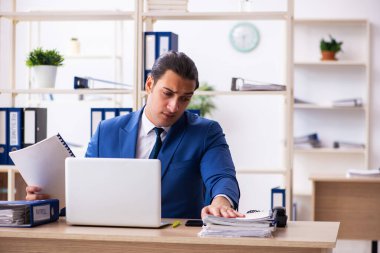 Genç yakışıklı çalışan ofiste oturuyor.