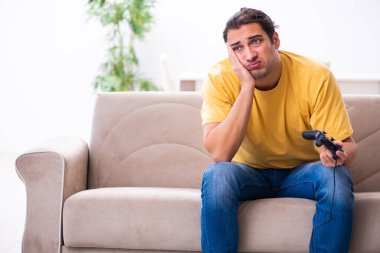 Genç adam evde joystick oynuyor.