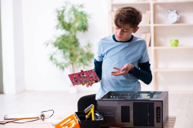 Çocuk atölyede bilgisayar tamir ediyor.