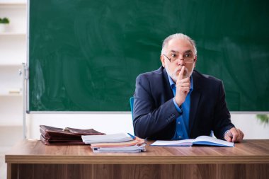 Sınıftaki yaşlı erkek matematik öğretmeni.