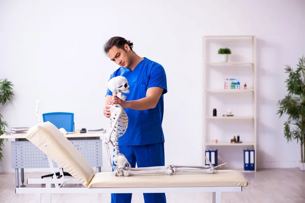 Jovem médico e esqueleto no sofá — Fotografia de Stock