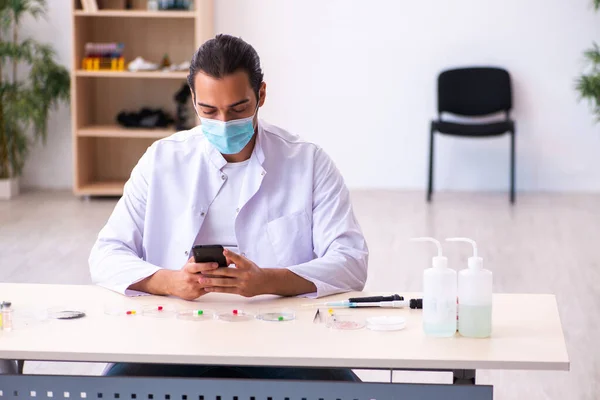 Jeune chimiste masculin travaillant dans le laboratoire pendant la pandémie — Photo