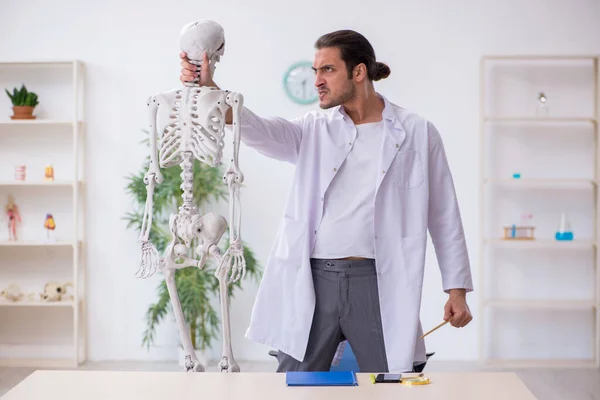 Jovem médico masculino demonstrando esqueleto humano — Fotografia de Stock