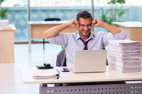 Jovem funcionário masculino infeliz com excesso de trabalho no escritório — Fotografia de Stock