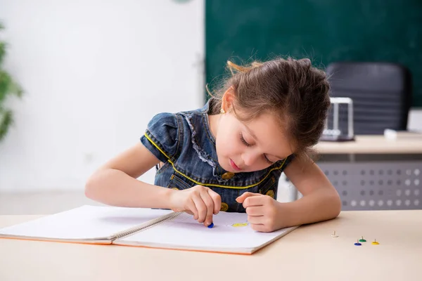 Menina pequena e thumbtacks na sala de aula — Fotografia de Stock